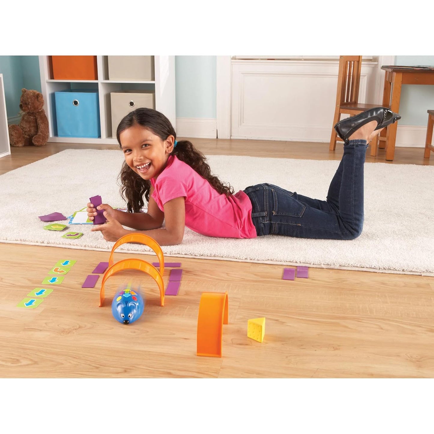 Young girl on the floor with the Learning Resources Rechargeable Code & Go Robot Mouse, guiding it through a coded obstacle course. Screen-free STEM learning for ages 4+, teaching coding through hands-on play.