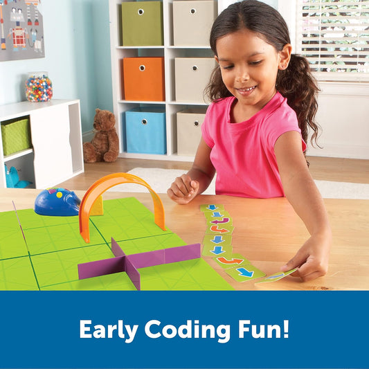 Young girl playing with the Learning Resources Rechargeable Code & Go Robot Mouse. Screen-free STEM learning for ages 4+, teaching coding through hands-on play.