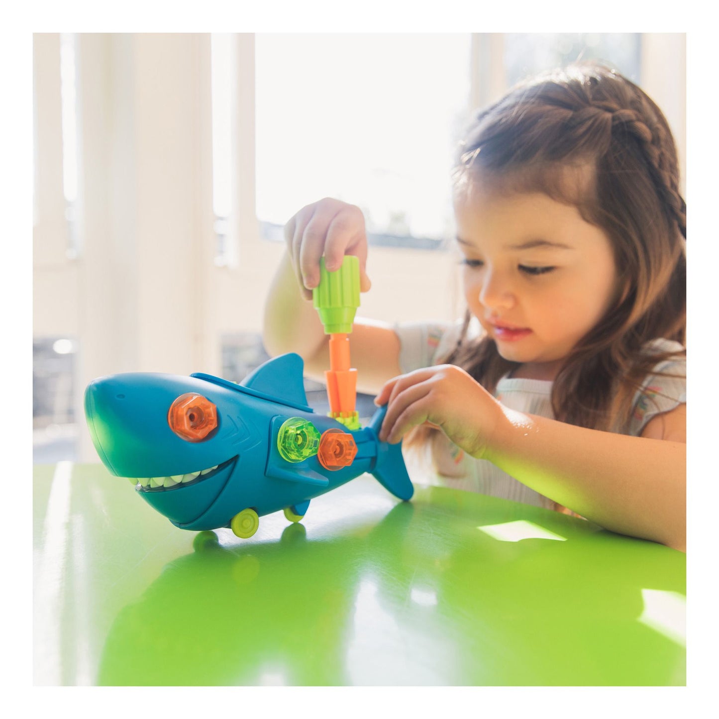 A child plays with the Educational Insights Design & Drill Shark, using a kid friendly screwdriver to secure colorful bolts. This rolling toy builds fine motor skills and early engineering concepts.