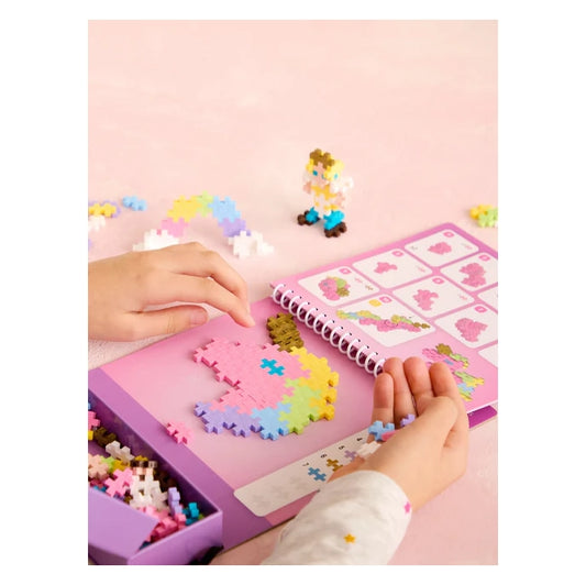 A close-up of a child assembling a 2D unicorn head using the Plus-Plus Puzzle By Number page, carefully matching colourful interlocking pieces to the numbered guide.