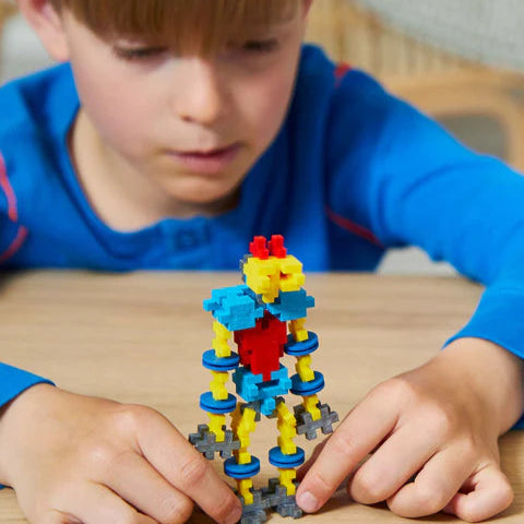 A child actively playing with a completed Plus-Plus robot model, engaging in hands-on creativity and imaginative play.