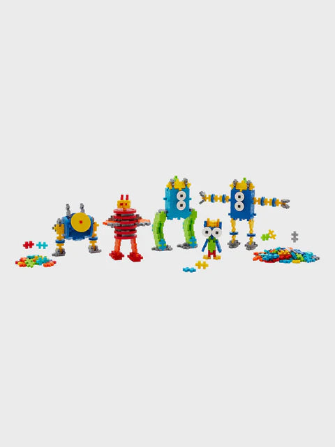 Five completed Plus-Plus robot models built from interlocking pieces, with colorful Plus-Plus pieces piled on each side, showcasing creative building options.