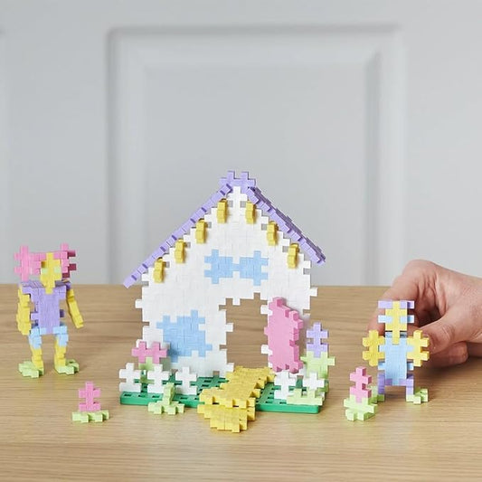 A model house and two Plus-Plus figures built from pastel coloured interlocking pieces