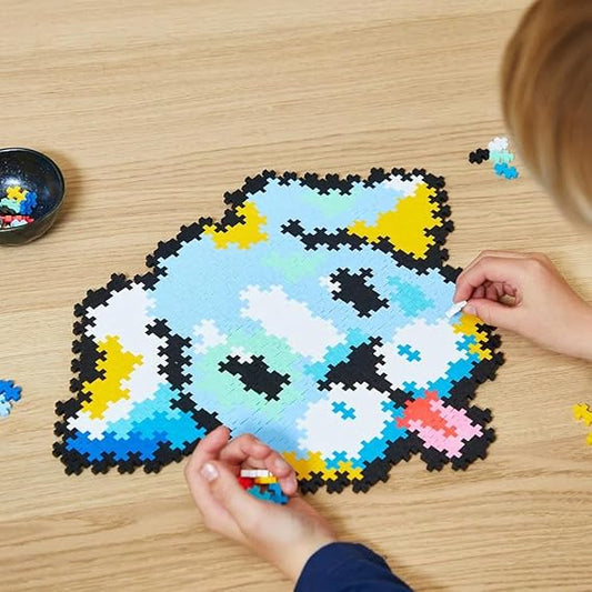 A completed Plus-Plus Puzzle By Number Puppy model, built from 500 colorful interlocking pieces, with a child placing the final piece to finish the design