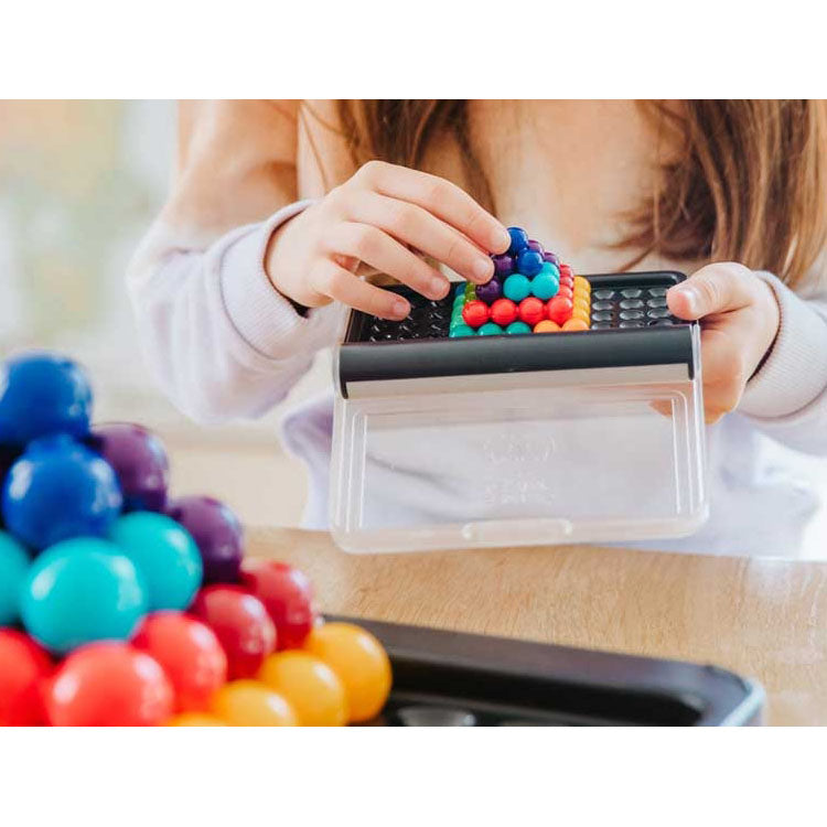child carefully assembling a 3D pyramid using colorful puzzle pieces on the SmartGames IQ Puzzler Pro board, engaging in hands-on logic and spatial reasoning.