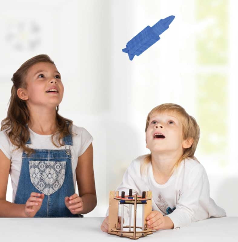 Two children excitedly watching a launched Smartivity Rocket soar through the air, having just activated the wooden launch pad, engaging in hands-on STEM learning about thrust and propulsion