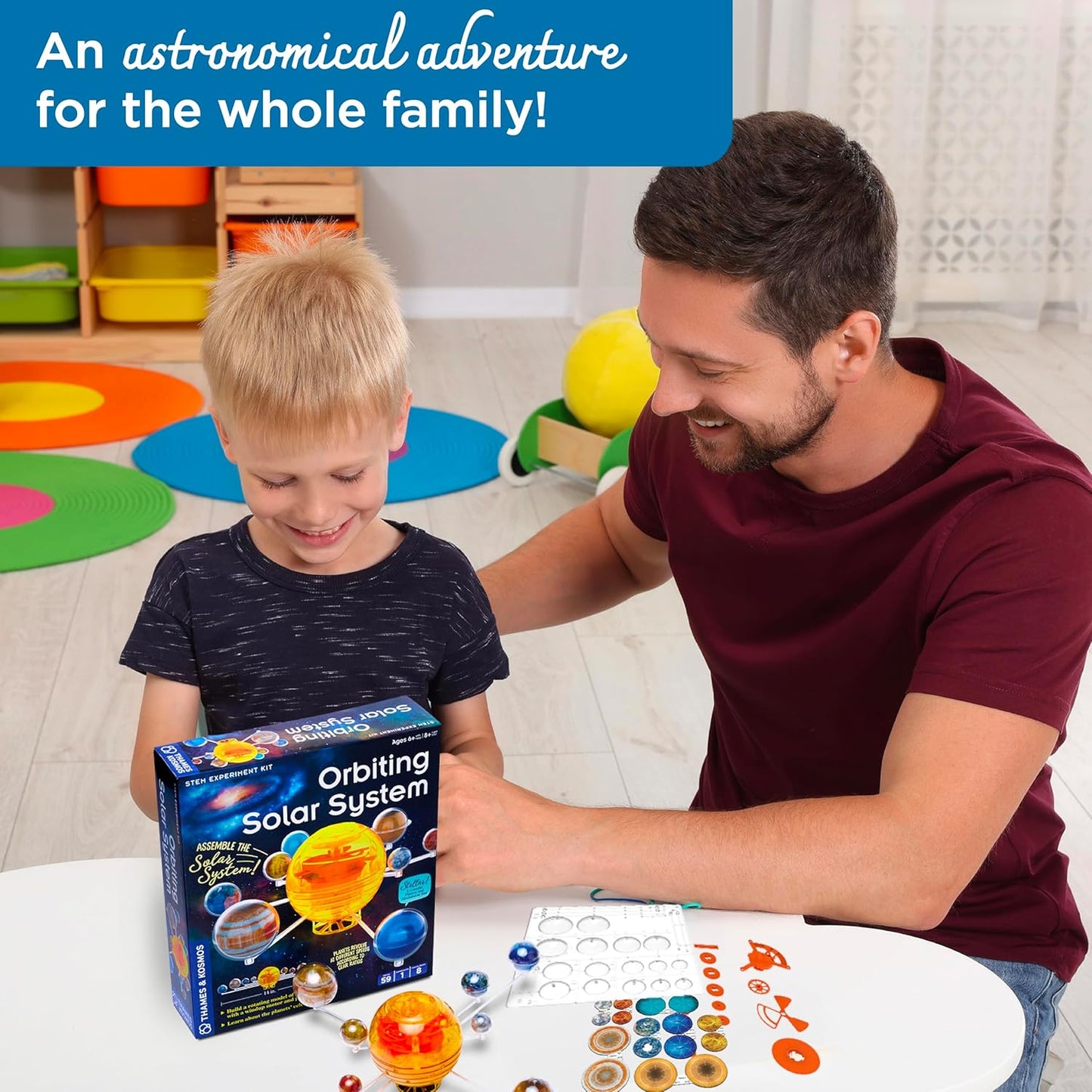 Dad and young son with the Thames & Kosmos Orbiting Solar System kit box and model parts. A hands-on STEM adventure exploring planetary motion together.