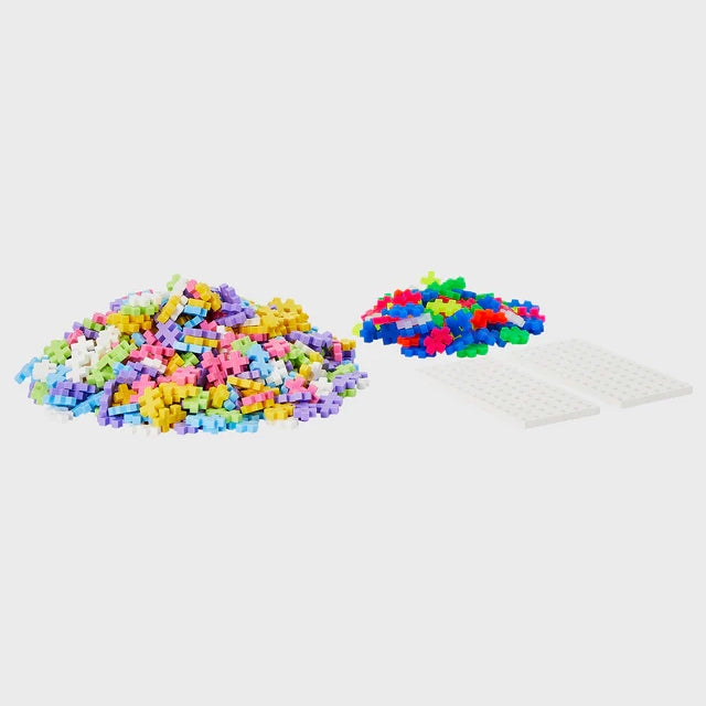 A pile of plus-plus interlocking puzzle like pieces, showing contents in a plus-plus pastel metal suitcase