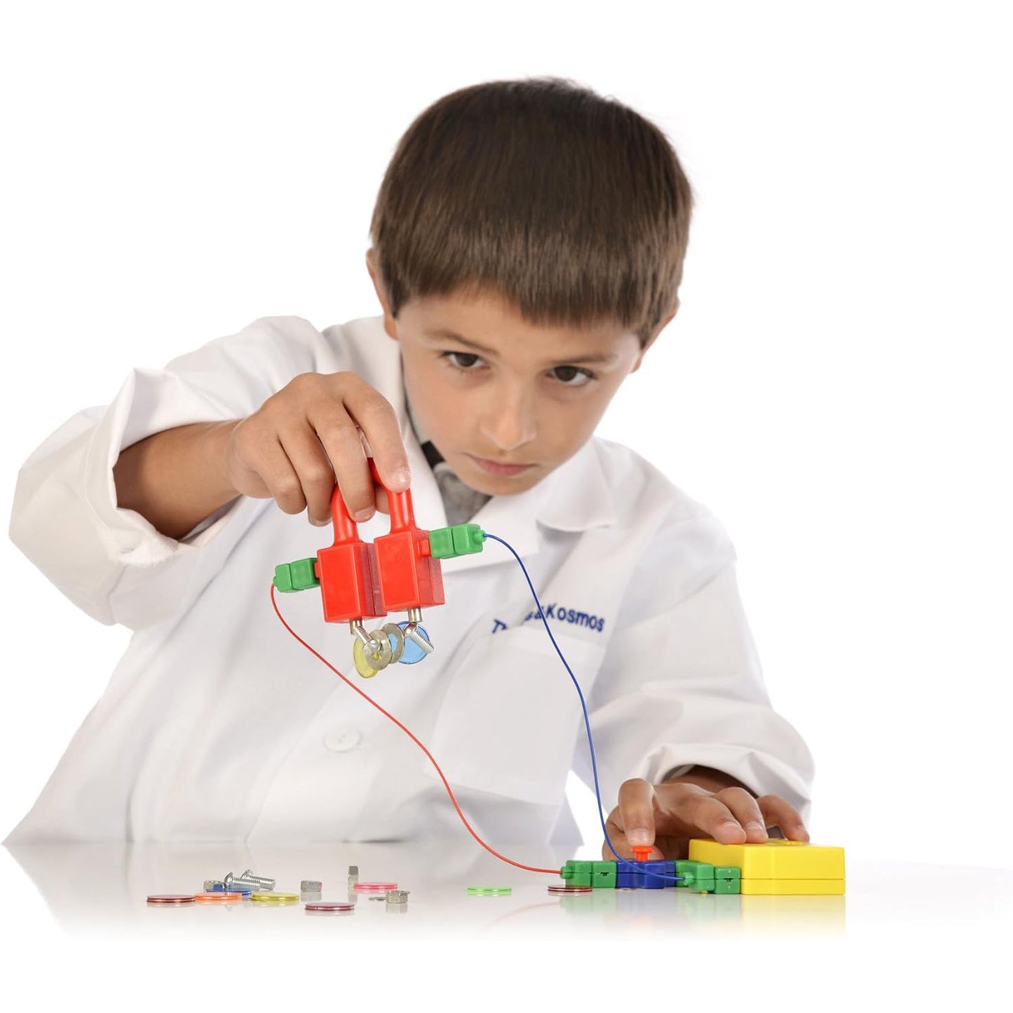 "A child carefully assembling an electrical circuit using colorful snap-together components from the Thames & Kosmos Electricity & Magnetism kit.